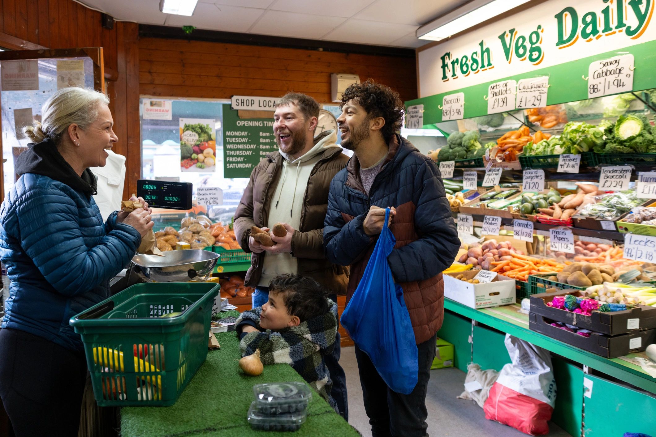 Family buying vegetables from a friendly shopkeeper